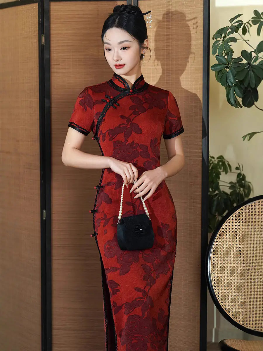 Woman wearing a Deep Red Floral traditional chinese Qipao Cheongsam Dress with Black Trim with black patterns indoors.