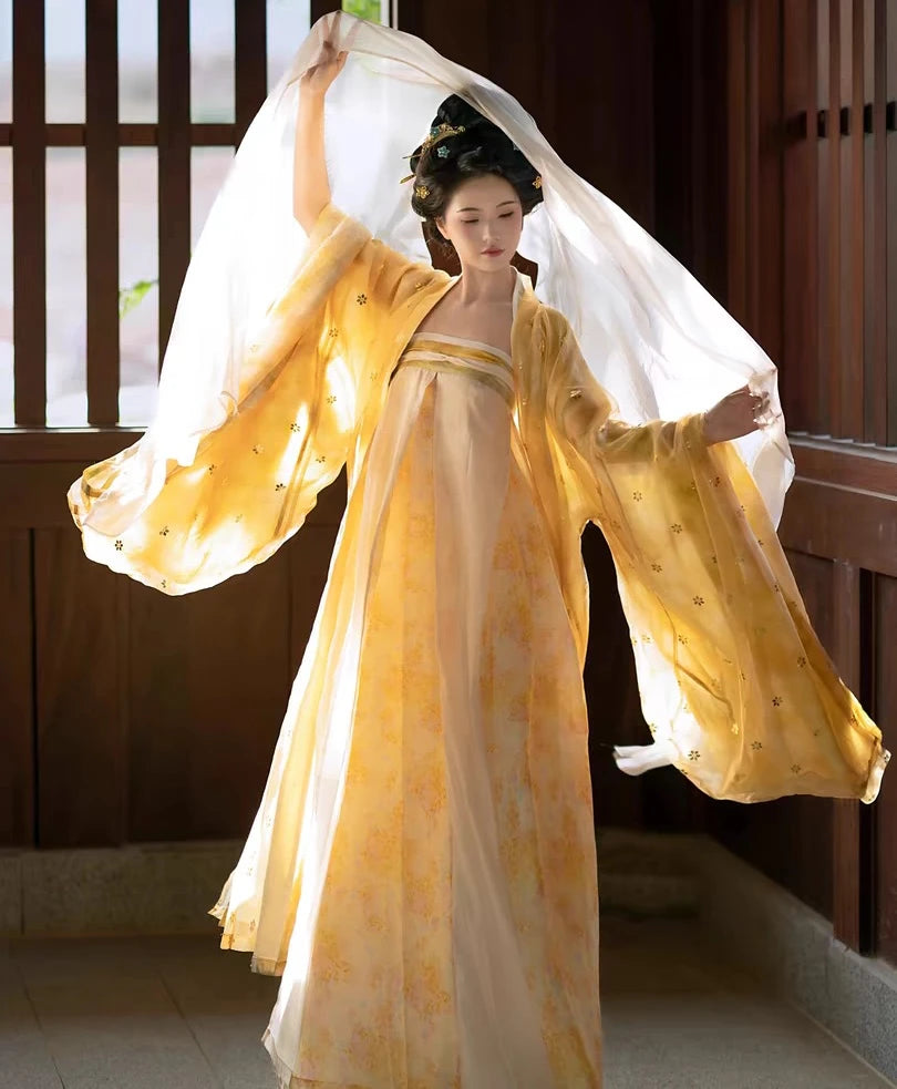 Woman in a  yellow Golden Traditional Chinese Tang Dynasty Hanfu Dress Set with a flowing train, standing indoors.