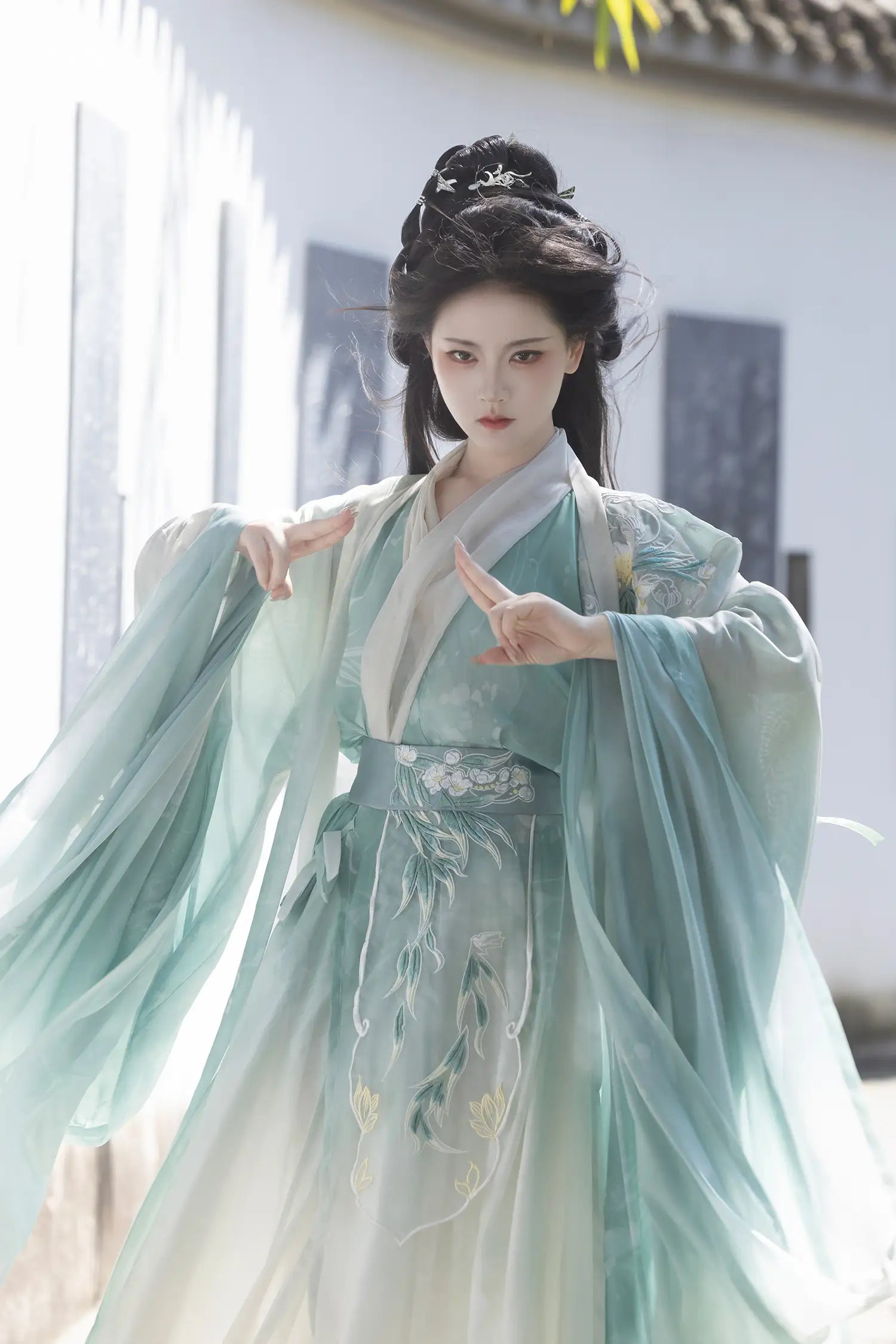 Person wearing traditional light Mint Green Wei-Jin Dynasty Flowing Robe Hanfu Dress e attire with floral patterns, standing outdoors.
