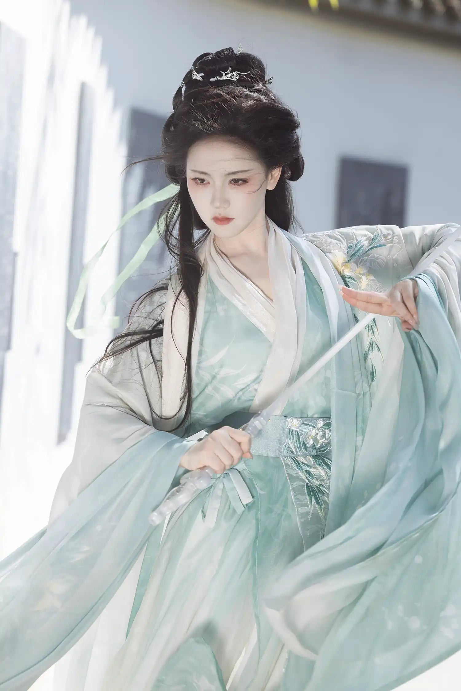 Person in traditional Chinese attire  Mint Green Wei-Jin Dynasty Flowing Robe Hanfu Dress with flowing sleeves against a blurred background