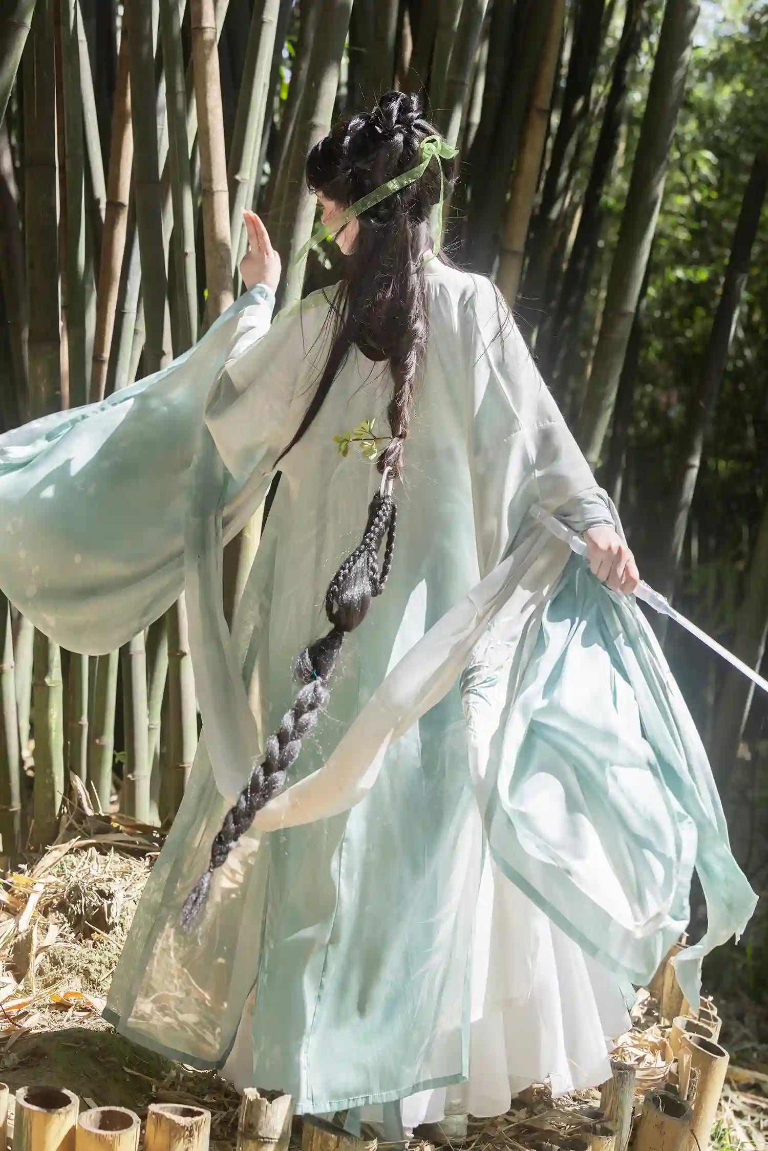 Person in traditional Mint Green Wei-Jin Dynasty Flowing Robe Hanfu Dressgarment with long braid standing in a bamboo forest