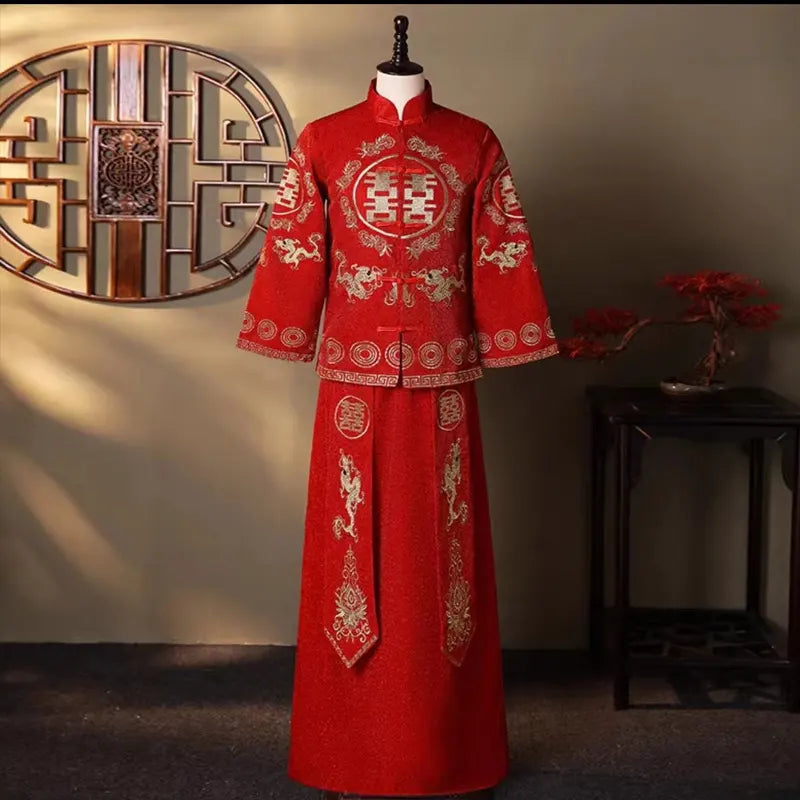 Traditional red wedding tang suit with gold embroidery on a mannequin against a decorative wall.