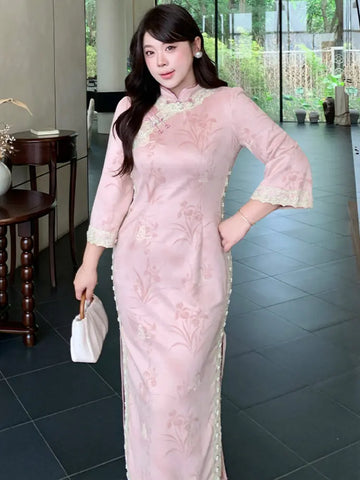 A woman modeling a light pink embroidered Plus size cheongsam dress with lace trim, holding a small white handbag in an indoor setting with dark tiled floors.