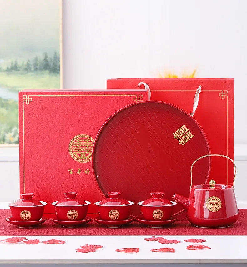 Red ceramic tea set with matching packaging on a white surface