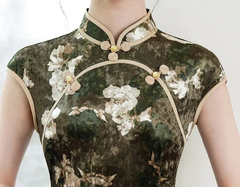 Traditional Chinese dress with floral patterns and gold accents on a plain background