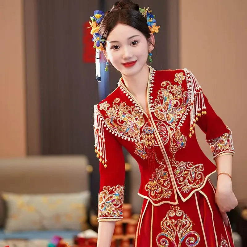 Woman in a traditional embroidered Modern Red Qun Kwa / Xiuhe Chinese Wedding Gown  outfit with decorative hairpiece indoors.