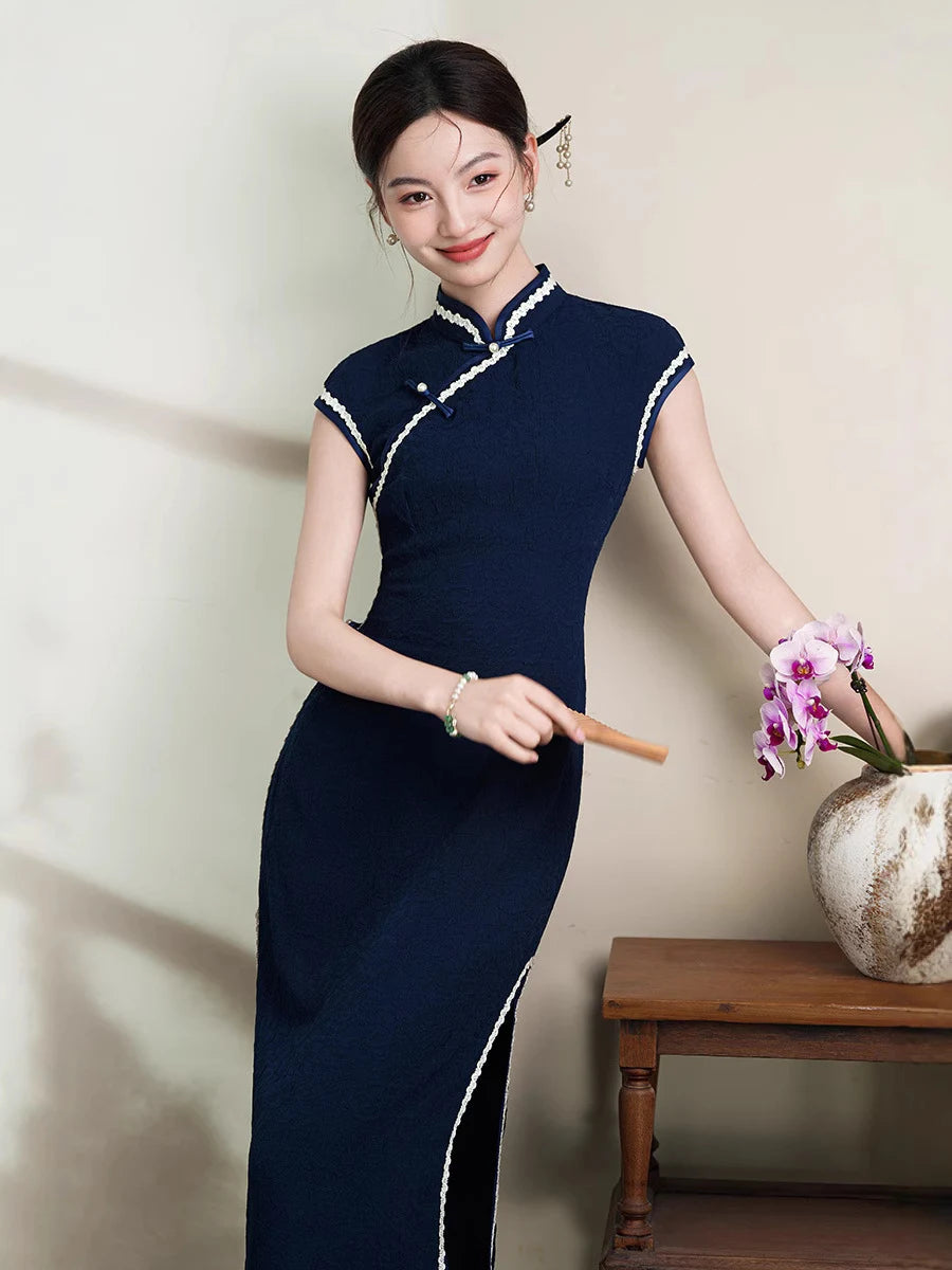 Woman in aNavy Blue Cap Sleeves Jacquard Cotton Qipao Dress  holding a flower and a fan indoors.