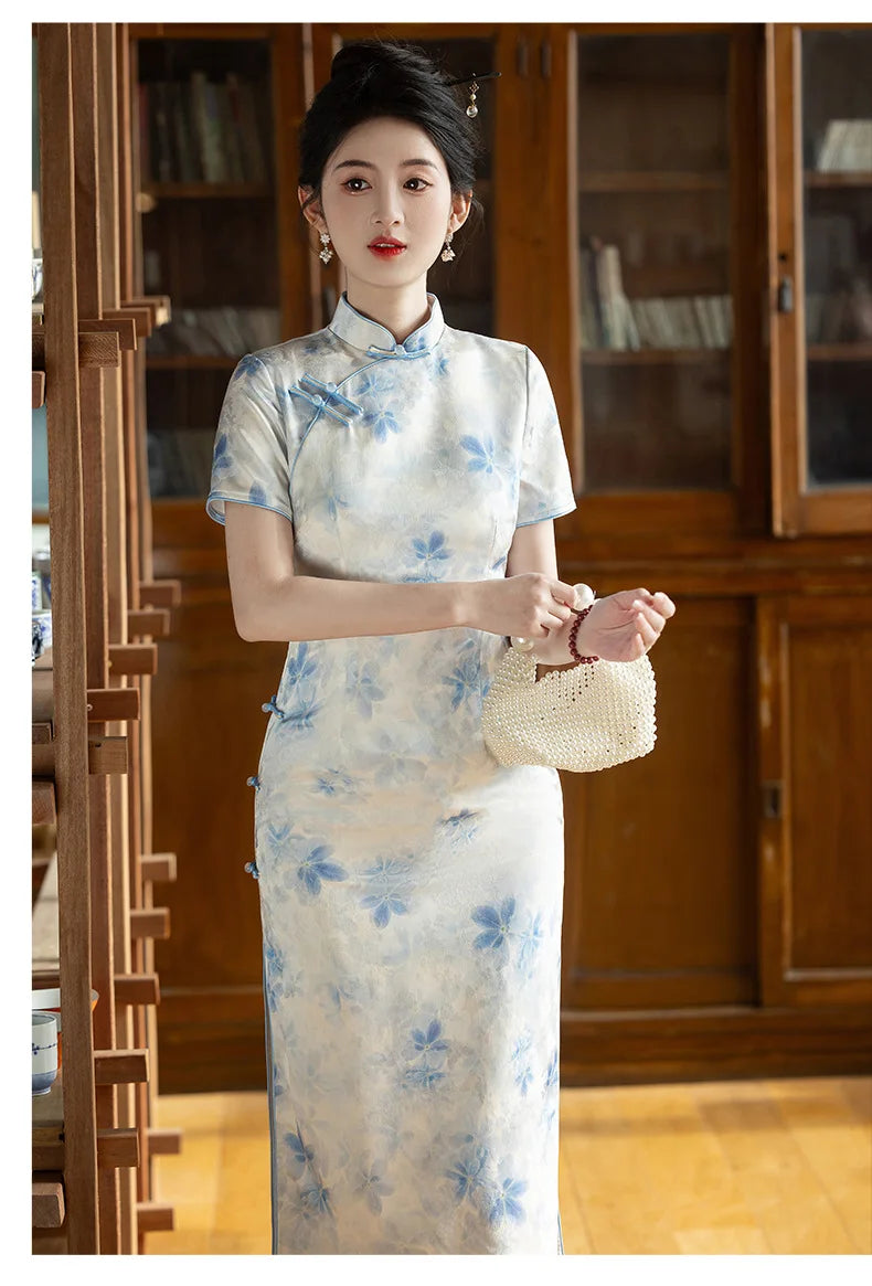 Woman wearing a Blue Watercolor Floral Long Qipao Cheongsam Dress s holding a woven bag in a room with wooden furniture.
