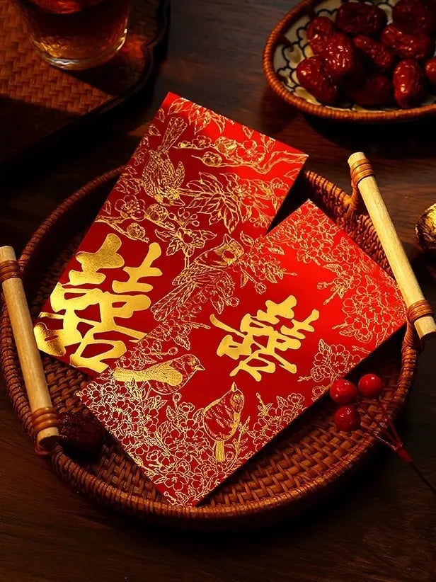 double happiness weddding Red envelopes with gold text on a woven tray with a bowl of red dates in the background.
