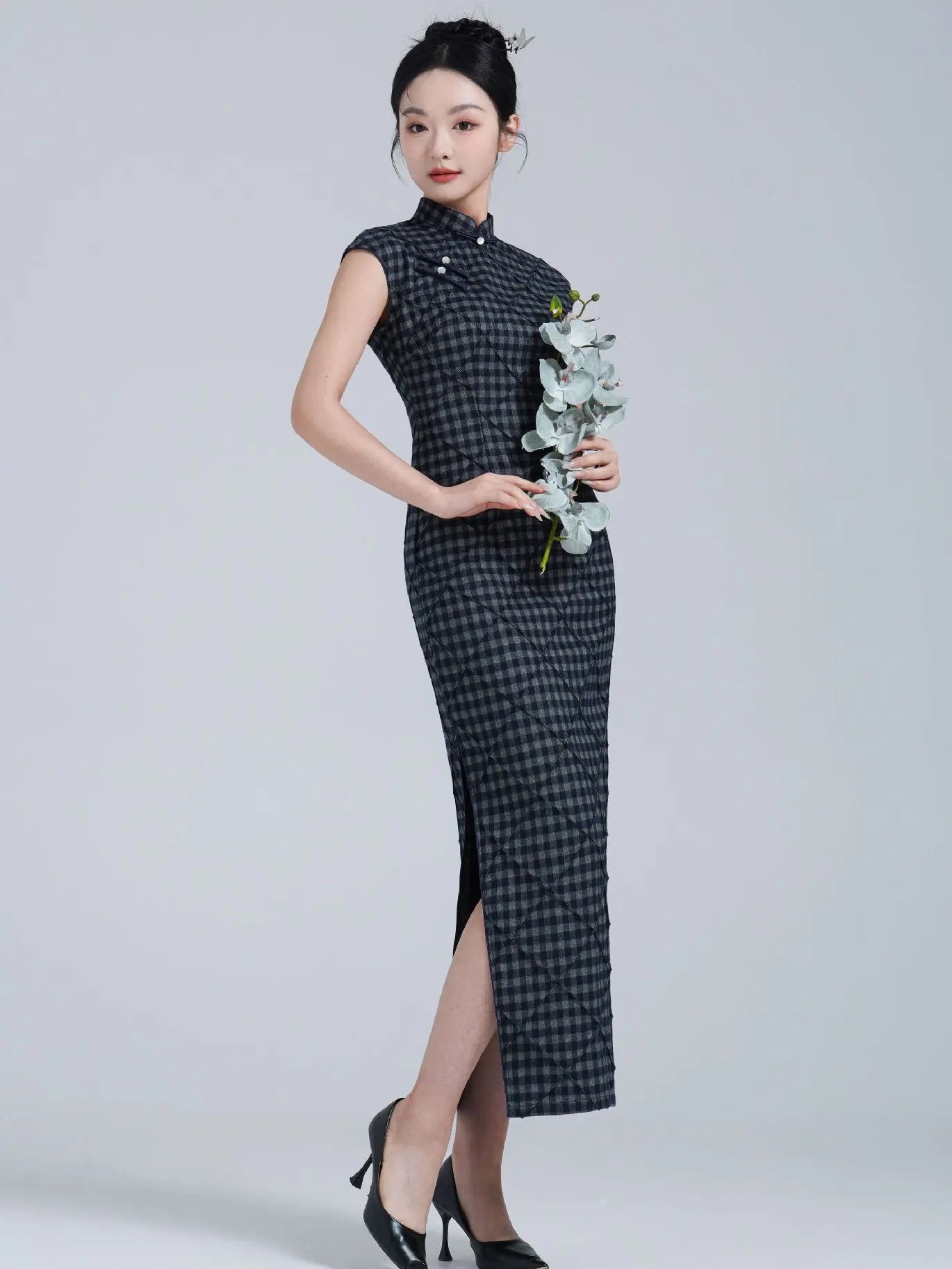 Woman wearing a Black Vintage Plaid Modern Cap Sleeve Qipao Dress holding flowers against a white background