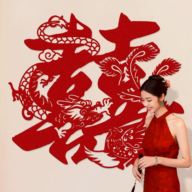 Woman in a red dress standing next to a large red double happiness symbol with dragon design on a beige background