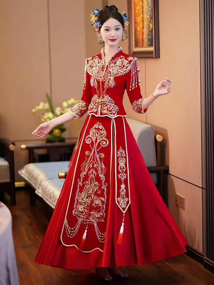 Woman in a traditional Modern Red Qun Kwa / Xiuhe Chinese Wedding Gown embroidered dress standing indoors.