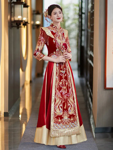 Woman in a traditional red and gold  Chinese Velvet Wedding Qun Kwa Dress standing in an indoor setting.