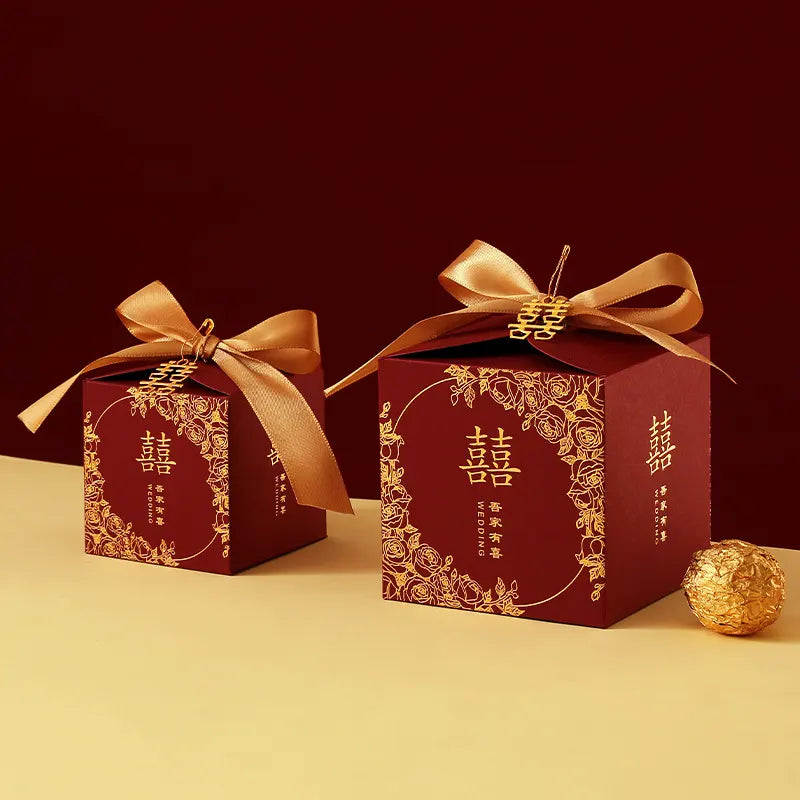 Red & Gold Double Happiness Chinese Wedding Favor Boxes  gift boxes with gold ribbons on a yellow surface with a dark red background