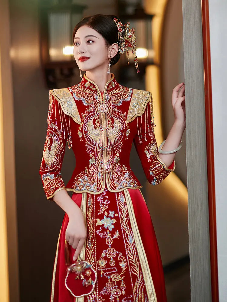 Woman in a traditional red and gold embroidered outfit with intricate designs- Chinese Velvet Wedding Qun gua Dress 