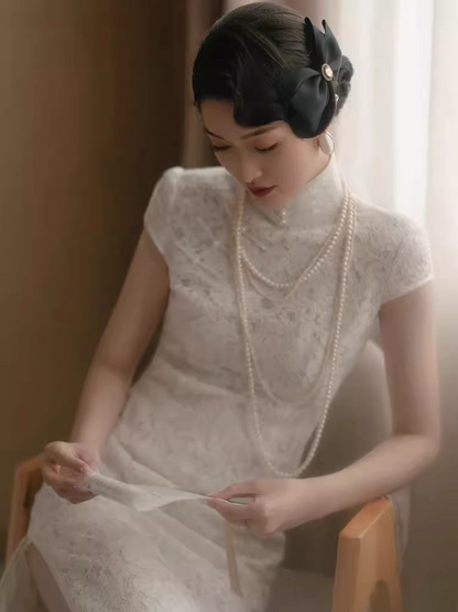 model in traditional chinese white lace cheongsam qipao sitting and looking down