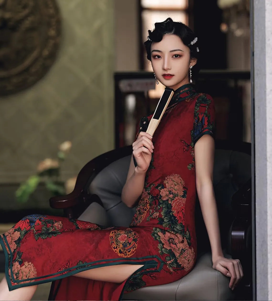 Woman in a traditional Vintage Red Chinese formal gown , Floral Qipao Cheongsam Dress  holding a broom in an indoor setting