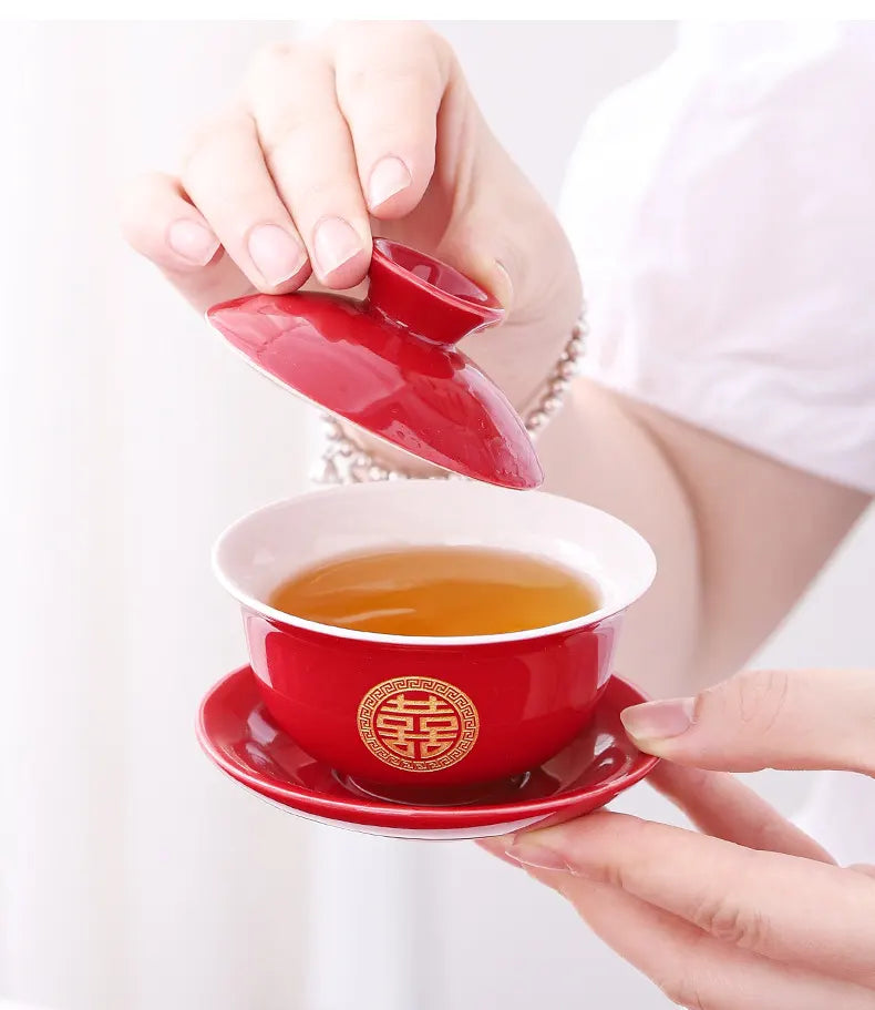 Red teacup with lid being lifted by a hand on a white background