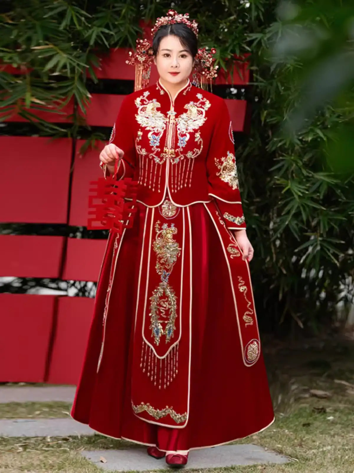 Person wearing a plus size Red Qun Kwa – Traditional Chinese Wedding Dress with gold details against a blurred natural background.