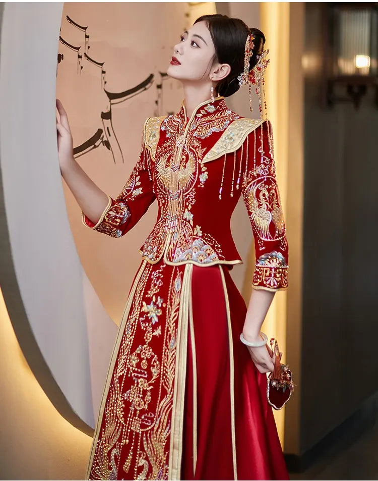 Woman in a traditional red and gold Chinese Velvet Wedding Qun Kwa Dress   with intricate patterns, standing against a blurred background.