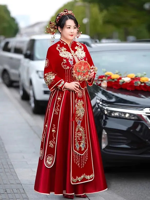 Woman in a plus size Red Qun Kwa – Traditional Chinese Wedding Dress with gold embroidery standing in front of a car.