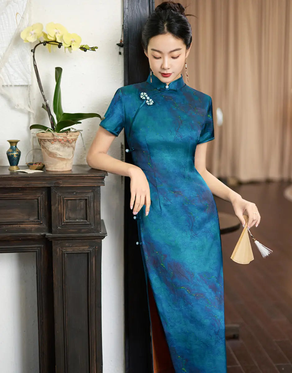 Woman in a Azure Blue Short Sleeve Acetate Satin Traditional cheongsam Qipao Dress standing indoors next to a fireplace.