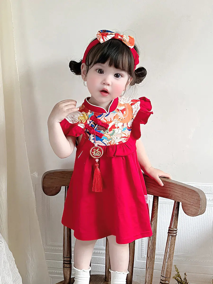 Child wearing a red traditional outfit Baby Girl Chinese Tang Style  Qipao Dress with Headband with decorative elements on a wooden chair.