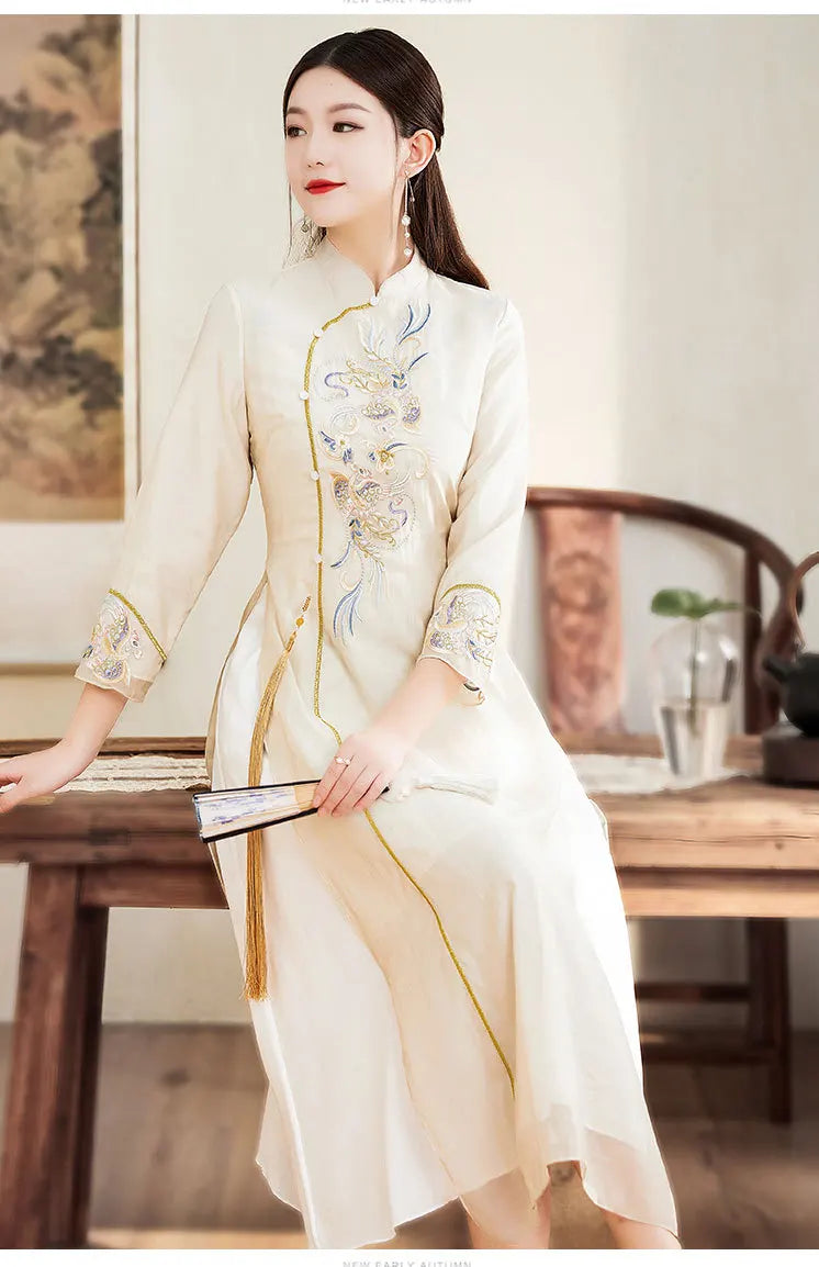 Woman in a traditional embroidered Beige Ao Dai Style Qipao Dres – A-Line Long Cheongsam  sitting at a wooden table in a classical setting.