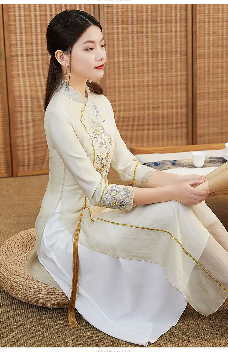 Woman in a traditional Beige Ao Dai Style Qipao Dres – A-Line Long Cheongsam  sitting on a woven mat.