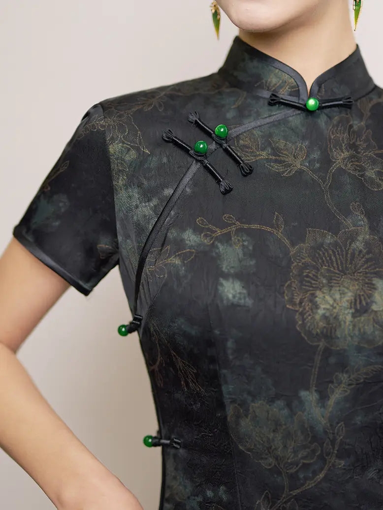 Black floral traditional outfit with green buttons on a plain background