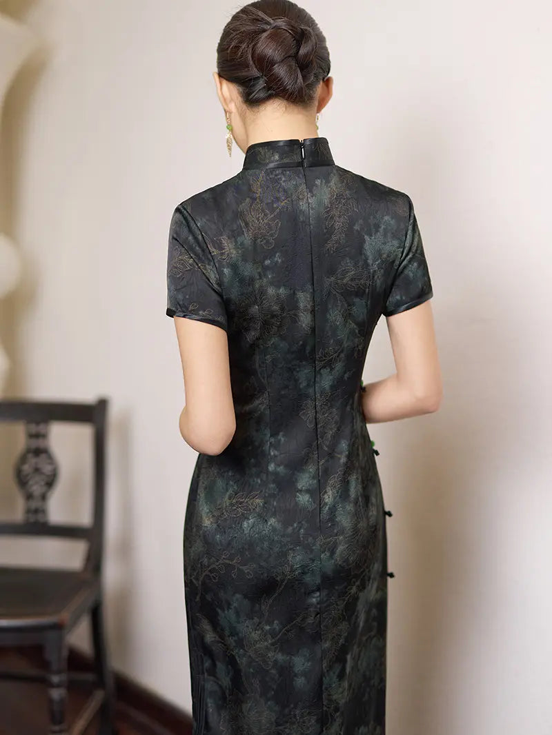 Woman wearing a Black & Deep Emeral Jacquard Satin Long Qipao With Green Buttons  with a blurred background