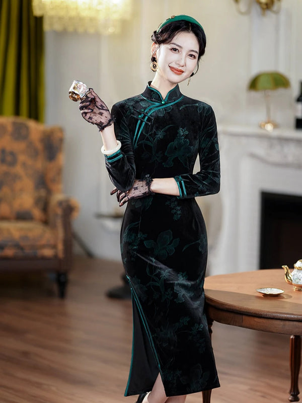 Woman in a Black & Emerald Green Velvet Long Sleeves Qipao Dress holding a phone in a room with a fireplace and chair.