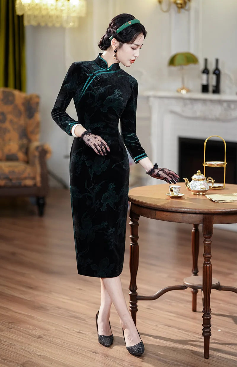 Woman in aBlack & Emerald Green Velvet Long Sleeves Qipao Dress standing in a room with wooden floors and a fireplace.