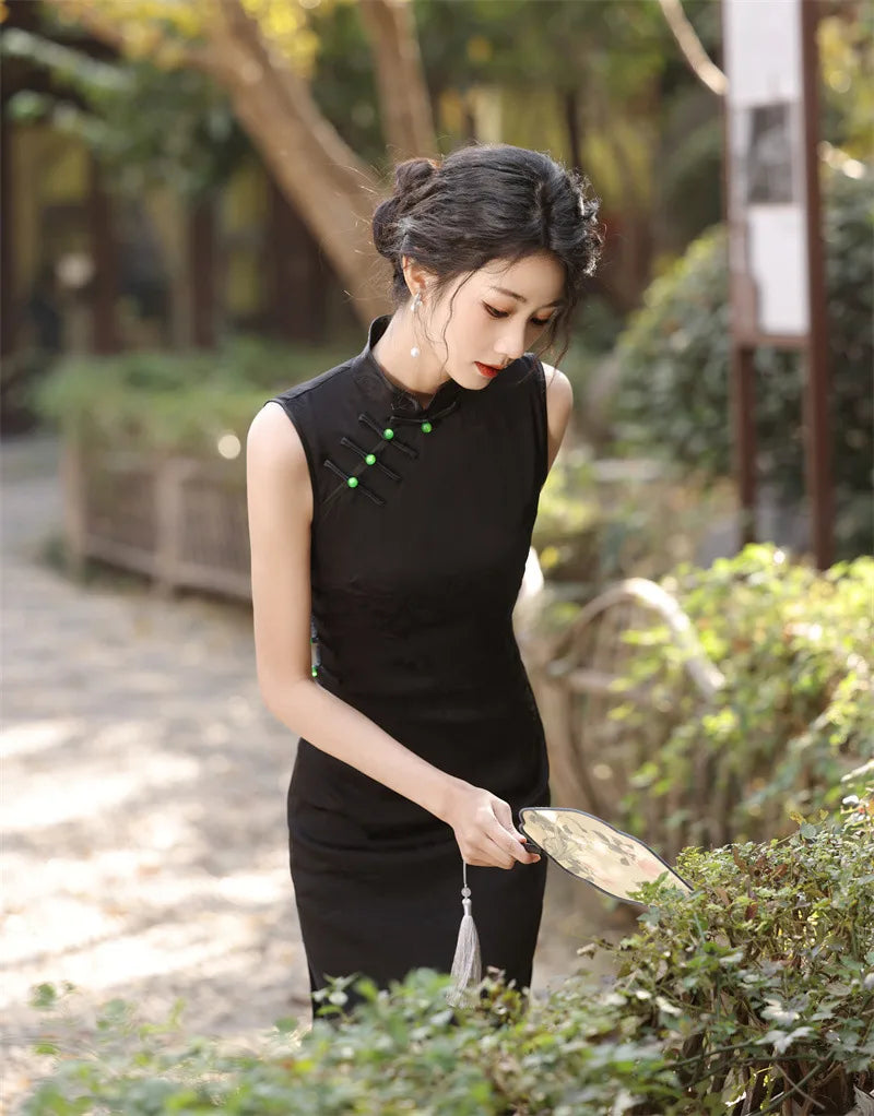 Woman in a Black Floral Jacquard Sleeveless Qipao Cheongsam Dress  with green buttons tending to plants outdoors.