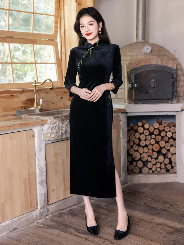 Woman in a Black Long Sleeves Qipao Dress with Green Embroidery  standing in a rustic kitchen.