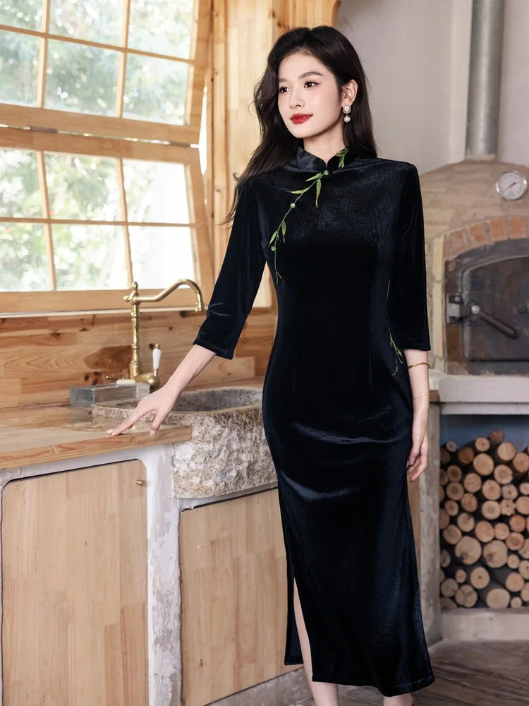 Woman in aBlack Long Sleeves Qipao Dress with Green Embroidery  standing in a rustic kitchen.