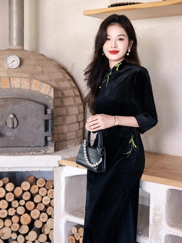 Woman in a Black Long Sleeves Qipao Dress with Green Embroidery  outfit holding a handbag in front of a brick oven.