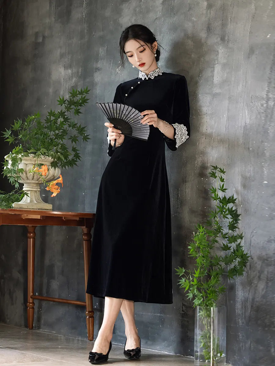 Woman in a Black Long Sleeves Velvet A-Line Qipao with Lace Trim  holding a fan against a gray wall with plants.