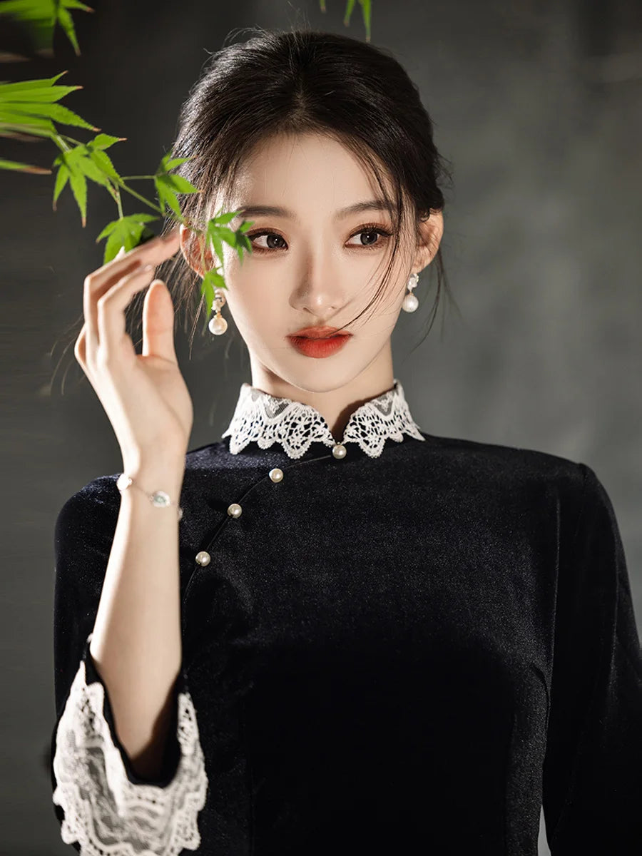 Woman wearing a Black Long Sleeves Velvet A-Line Qipao with Lace Trim , holding green leaves against a dark background