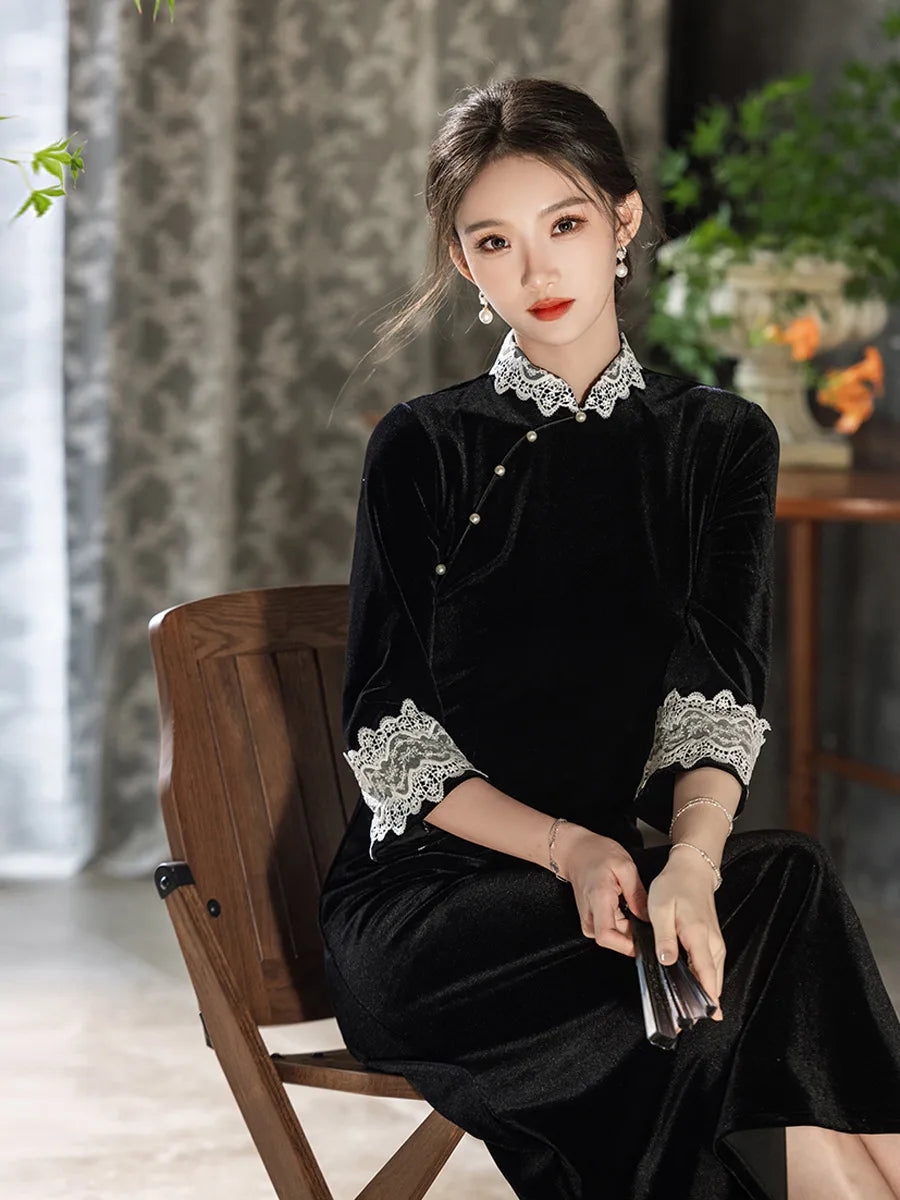 Woman in a Black Long Sleeves Velvet A-Line Qipao with Lace Trim  details sitting on a wooden chair.