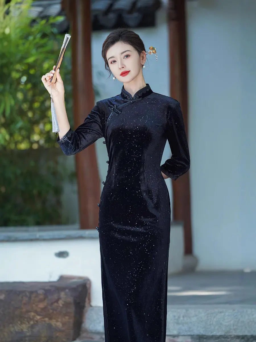 Woman in a black traditional Long Sleeves Velvet Chinese Qipao Dress holding a fan outdoors.