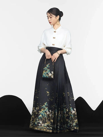 A woman models a traditional Chinese Hanfu outfit consisting of a white high-collar blouse and a long black pleated mamian horse face skirt with a detailed multicolor landscape print. She is holding a matching handbag against a clean white studio background.