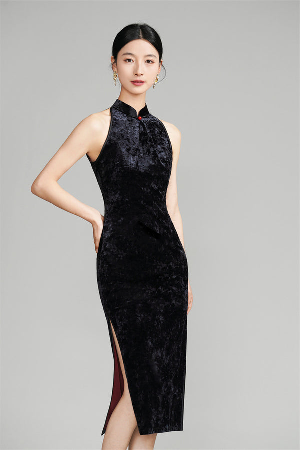 A woman wearing a black halter neck velvet qipao with a fitted silhouette and midi length.