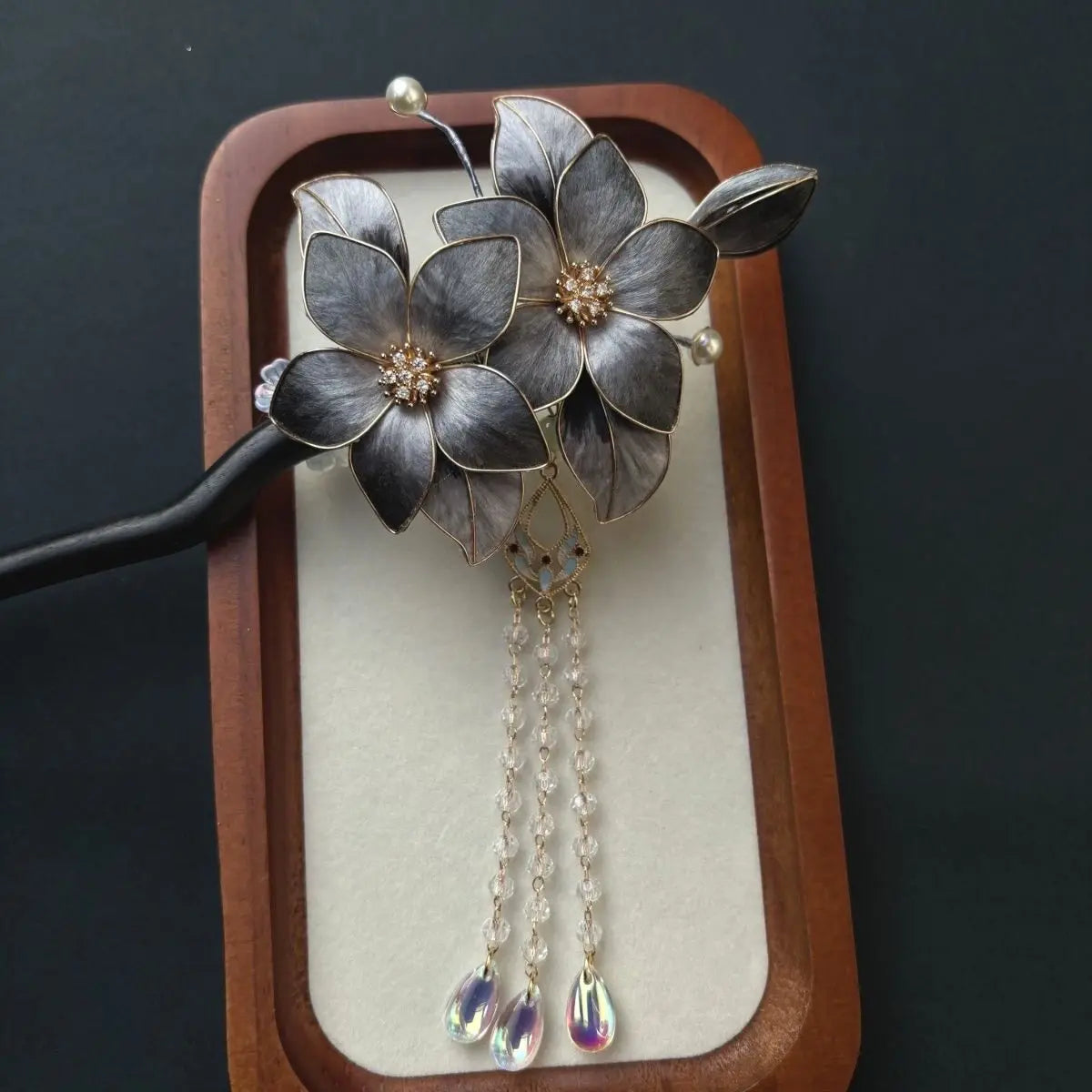 Black Sandalwood Ronghua Velvet Flower Hair Stick with Tassel on a wooden stand against a dark background