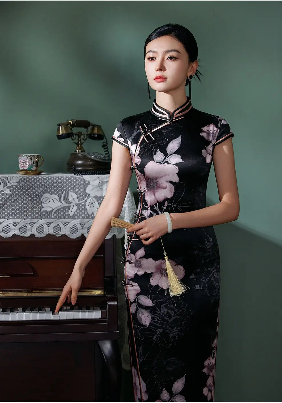 Woman in aBlack Silk Chinese Qipao Dress – Elegant Mandarin Collar Cheongsam  standing next to a piano in a vintage room.