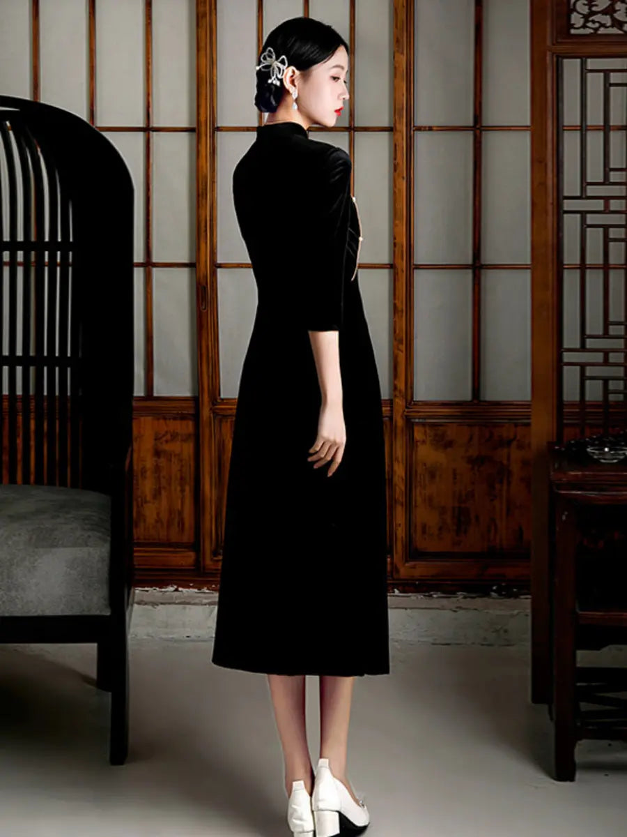 Woman in a Black Velvet A line Qipao Cheongsam with Faux Pearl Buttons standing in a traditional room with wooden paneling.