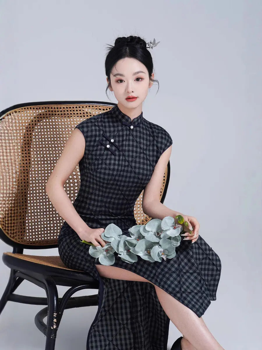 Woman in a Black Vintage Plaid Modern Cap Sleeve Qipao Cheongsam Dress dress holding flowers, sitting on a wicker chair against a plain background