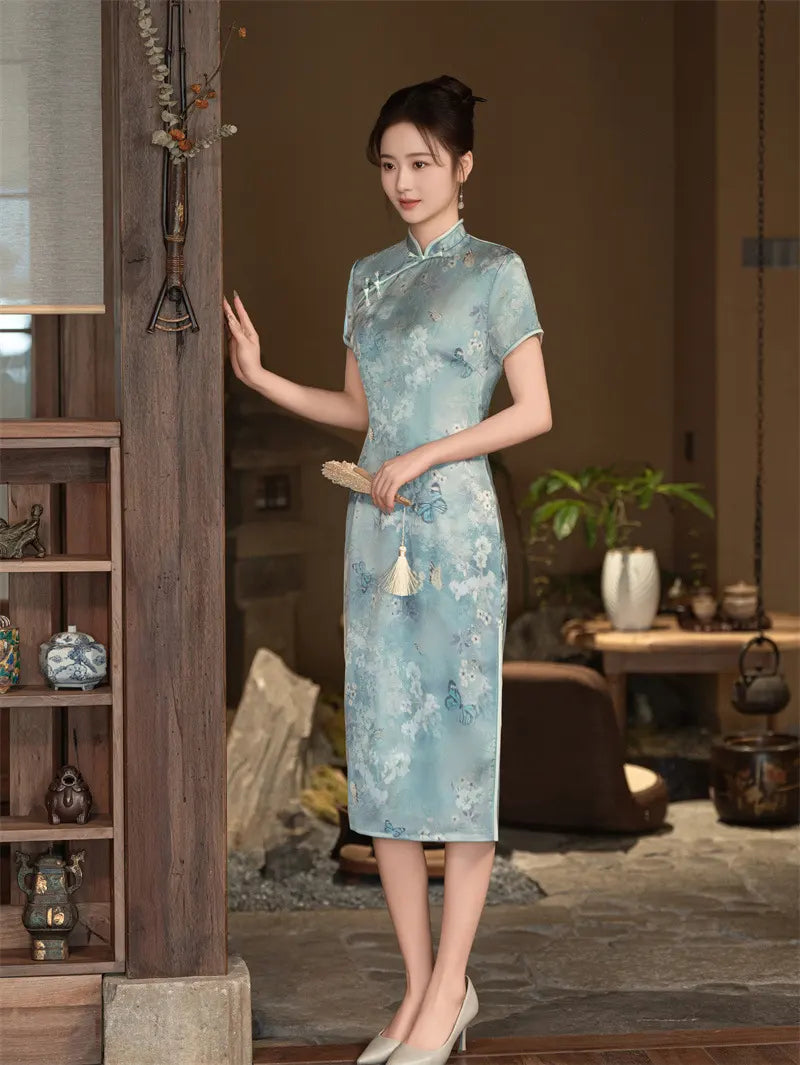 Woman in a light blue Floral Cheongsam Qipao Dress standing in a room with wooden furniture and decor.