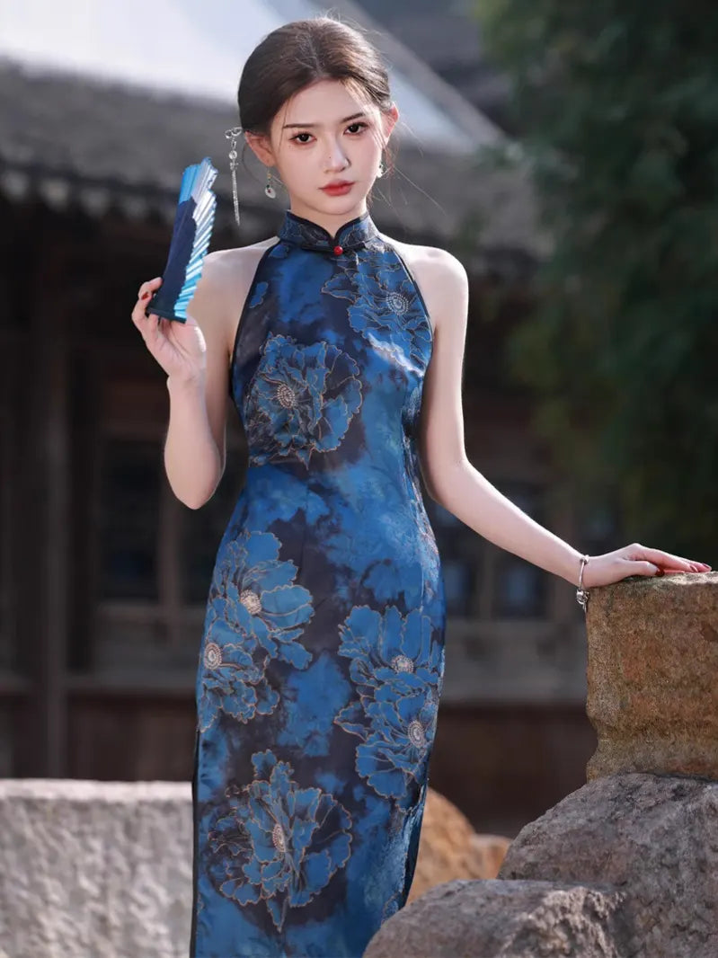 Woman in a Blue Floral Halter Chinese Qipao Cheongsam Dress  holding a fan outdoors.