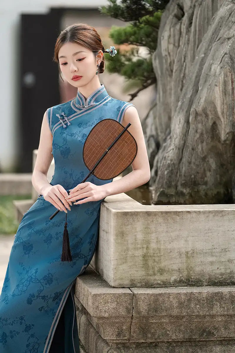Woman in a Blue Jacquard Sleeveless Midi Chinese cheongsam  Dress holding a wooden fan, standing in a garden setting.